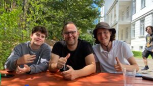Two students with their teacher in a campus park