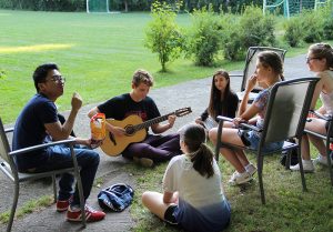 A students playing guitar with other students listening