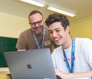 Teacher and student in front of a Macbook